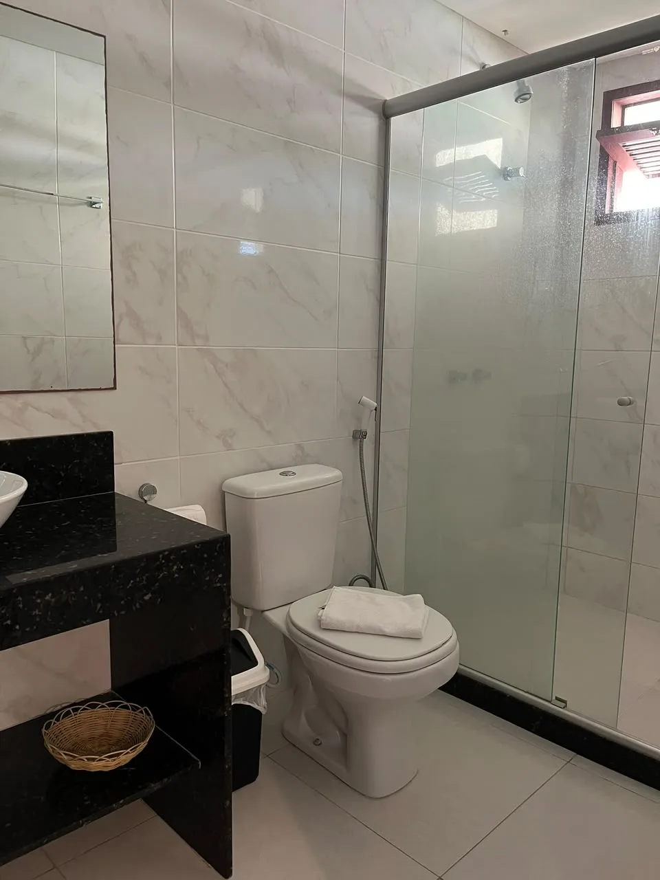 Banheiro com box de vidro e revestimento em mármore claro