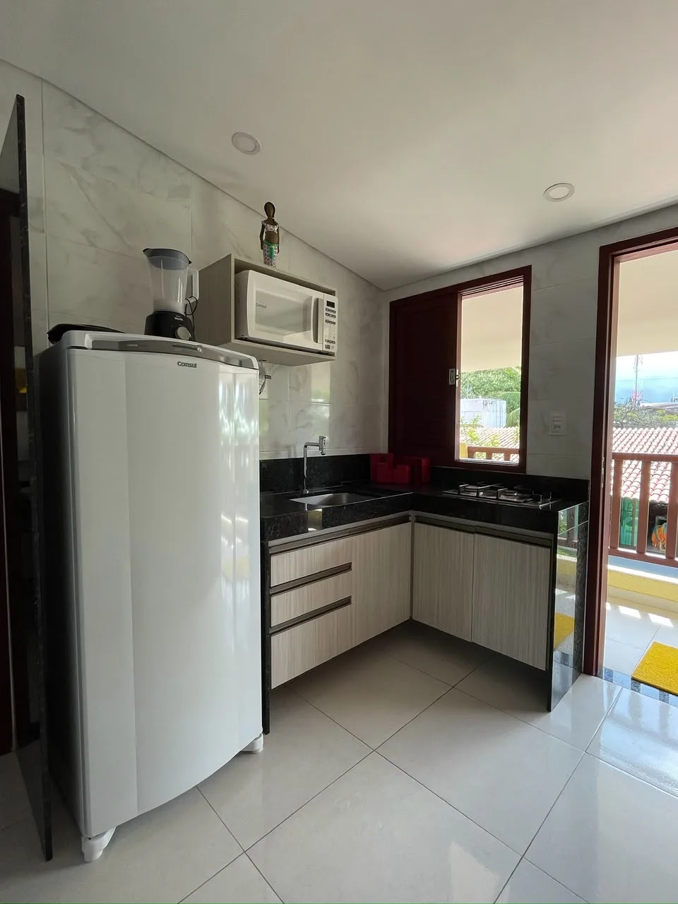 Cozinha com geladeira, micro-ondas, liquidificador e bancada