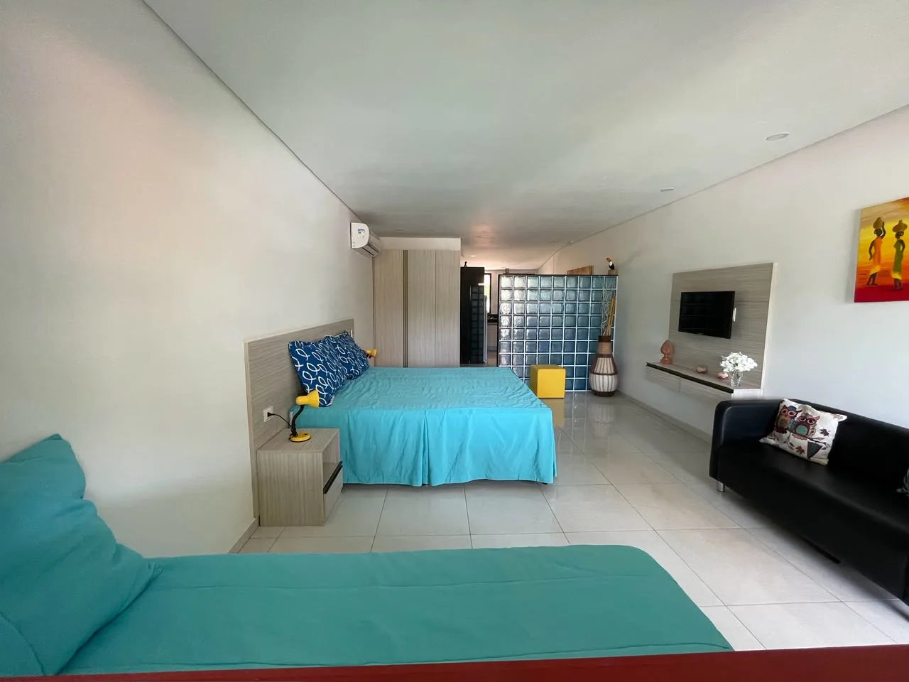 Estúdio amplo com camas, sofá, TV e cozinha integrada