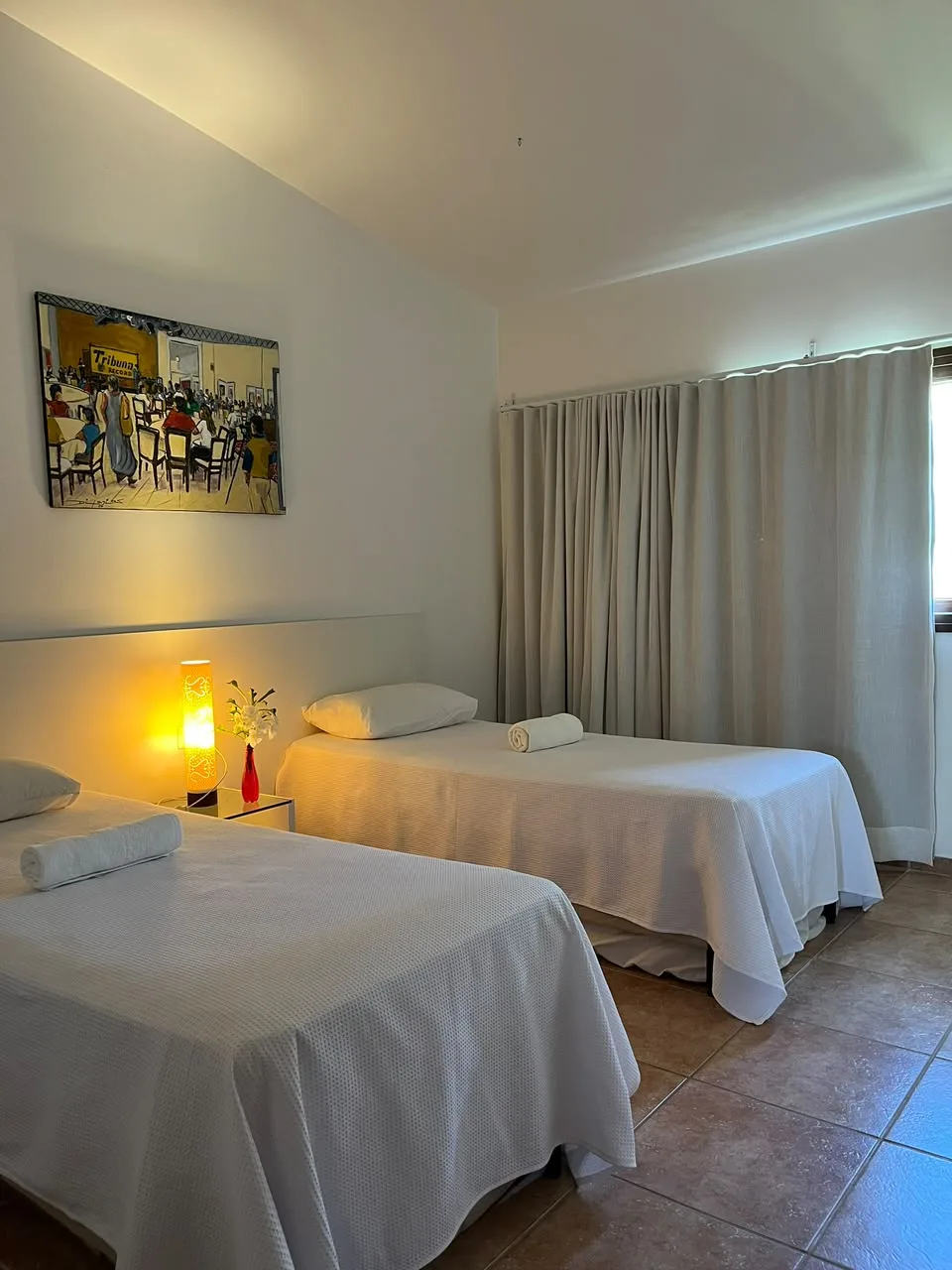 Quarto com duas camas arrumadas com lençóis brancos